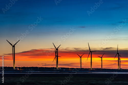 Wind turbines or wind energy converter in sunset time with rosy clouds in background