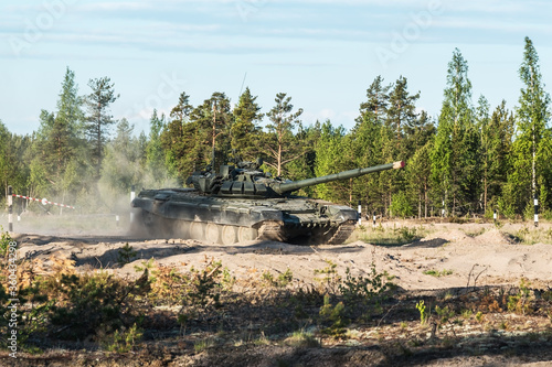 battle tank rides on a dusty road in the forest. Advanced tank of the Russian army t-90