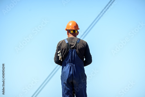  road worker in a hard hat and overalls. Construction of roads and bridges in the city.
