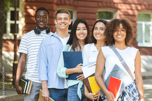 Group of smiling multicultural students posing near university campus