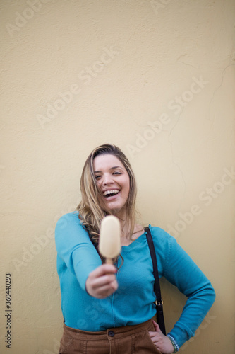 Blonde girl is eating ice-cream on a colarated background photo