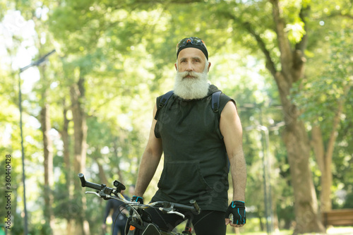 Senior man on cycle ride in countryside. Bearded mature man cycling.