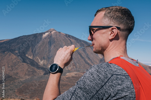 Portrait of young man eat sports nutrition energy gel while sitting and resting after trail running