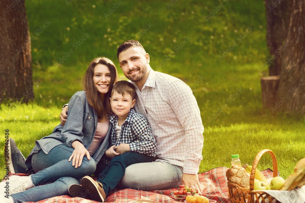 Happy family with cute child enjoying their time on picnic in park, blank space Happy family with cute child enjoying their time on picnic in park, blank space