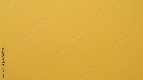 Stop motion animation of cup filling up with coffee beans on yellow