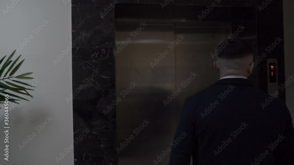 Mature businessman leaves a hotel room walks along the corridor of the hotel to the elevator Mature businessman leaves a hotel room walks along the corridor of the hotel to the elevator