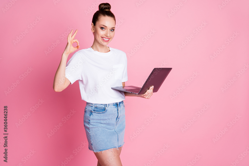 Photo of positive girl enjoy remote use laptop show okay sign wear white t-shirt denim jeans isolated over pastel color background Photo of positive girl enjoy remote use laptop show okay sign wear white t-shirt denim jeans isolated over pastel color background