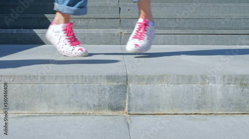 A happy teenage girl is dancing a shuffle on the stairs and enjoying life next to a modern building. The concept of carefree, youth culture and city life photo