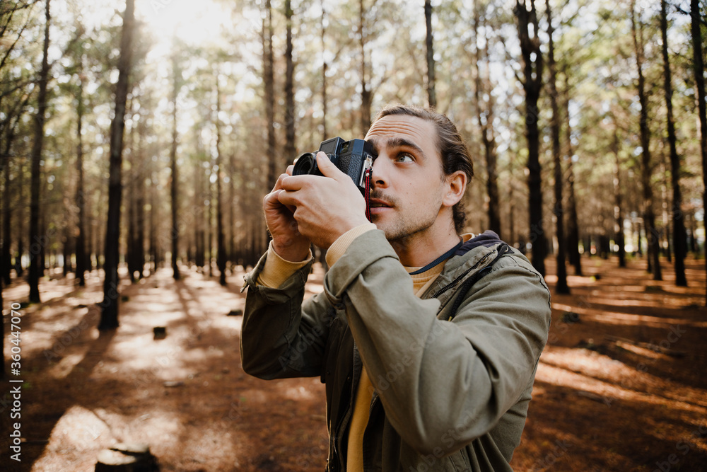 Young male photographer in the woods taking pictures with his film camera Young male photographer in the woods taking pictures with his film camera