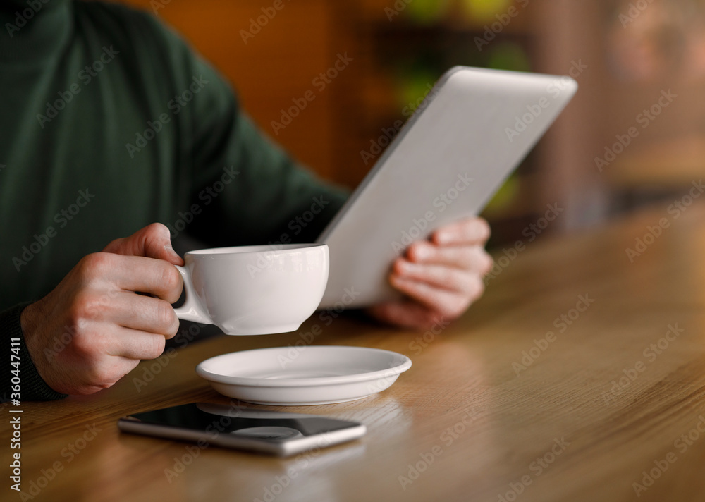 Man hands holding cup of coffee and digital tablet Man hands holding cup of coffee and digital tablet