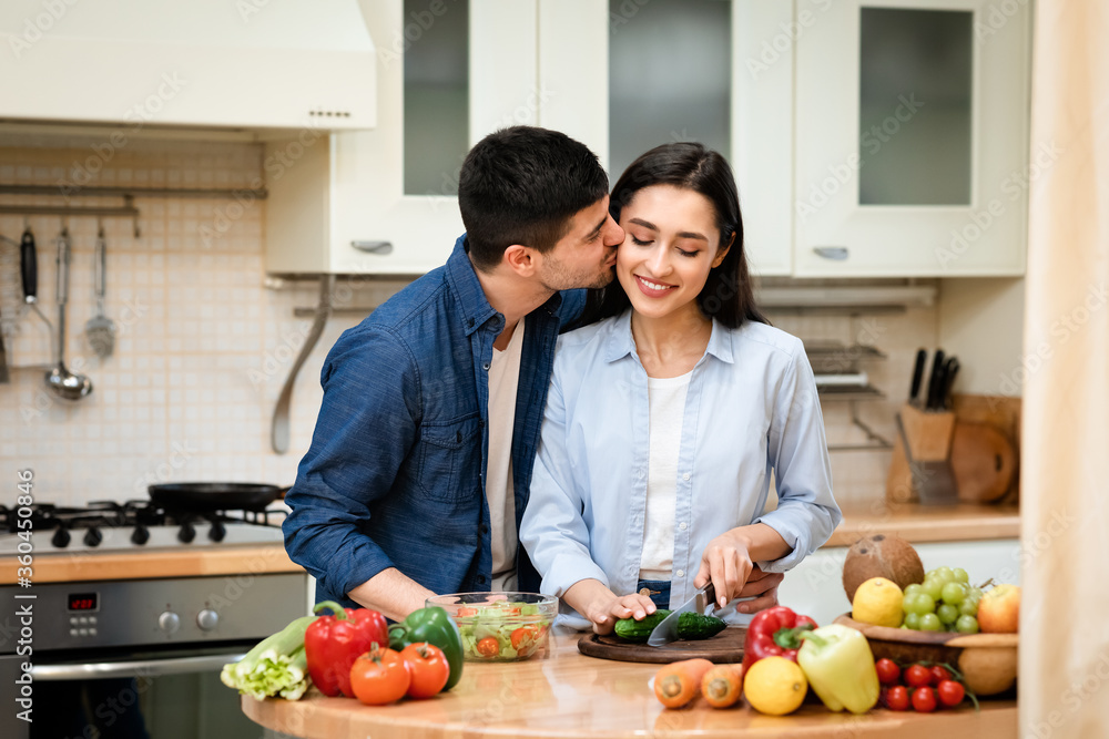 Lovely couple preparing dinner cutting vegetables at home
