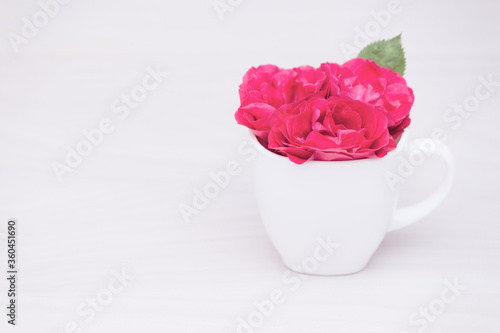 Flowers red roses in a cup on wooden background. Flat lay, top view, floral background, toned.