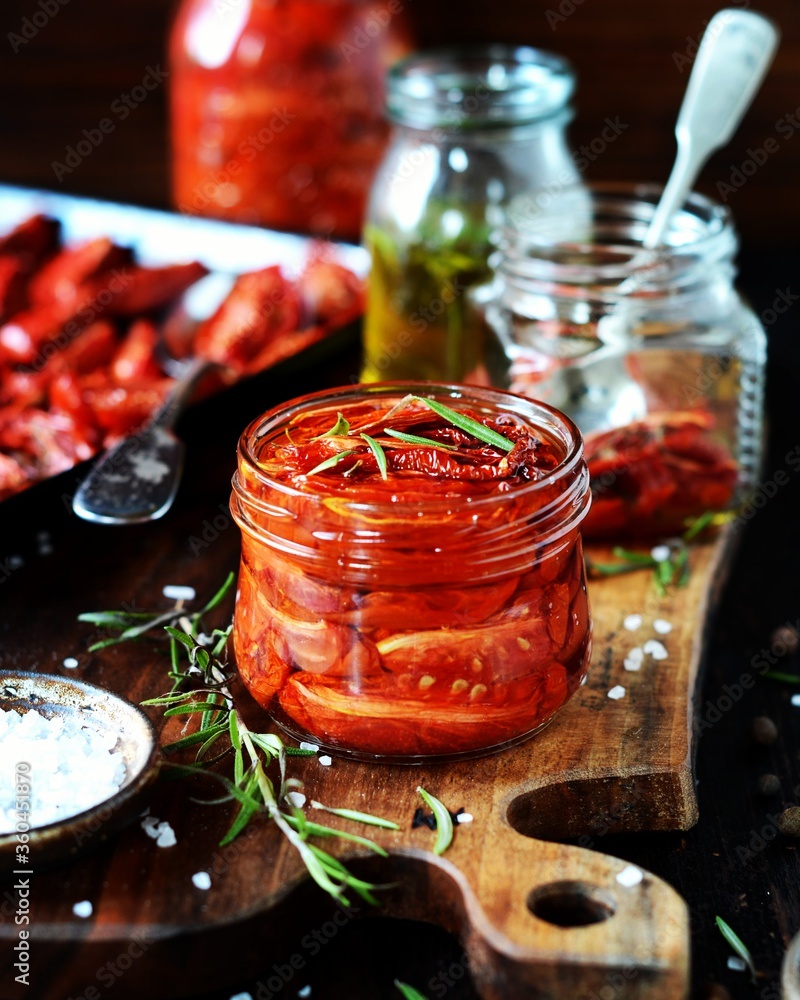 Homemade dried tomatoes in glass jars on a dark background, still life Homemade dried tomatoes in glass jars on a dark background, still life