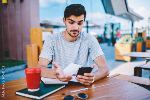 Canvas Print Skeptical male blogger amazed with incoming notification with strange message ab