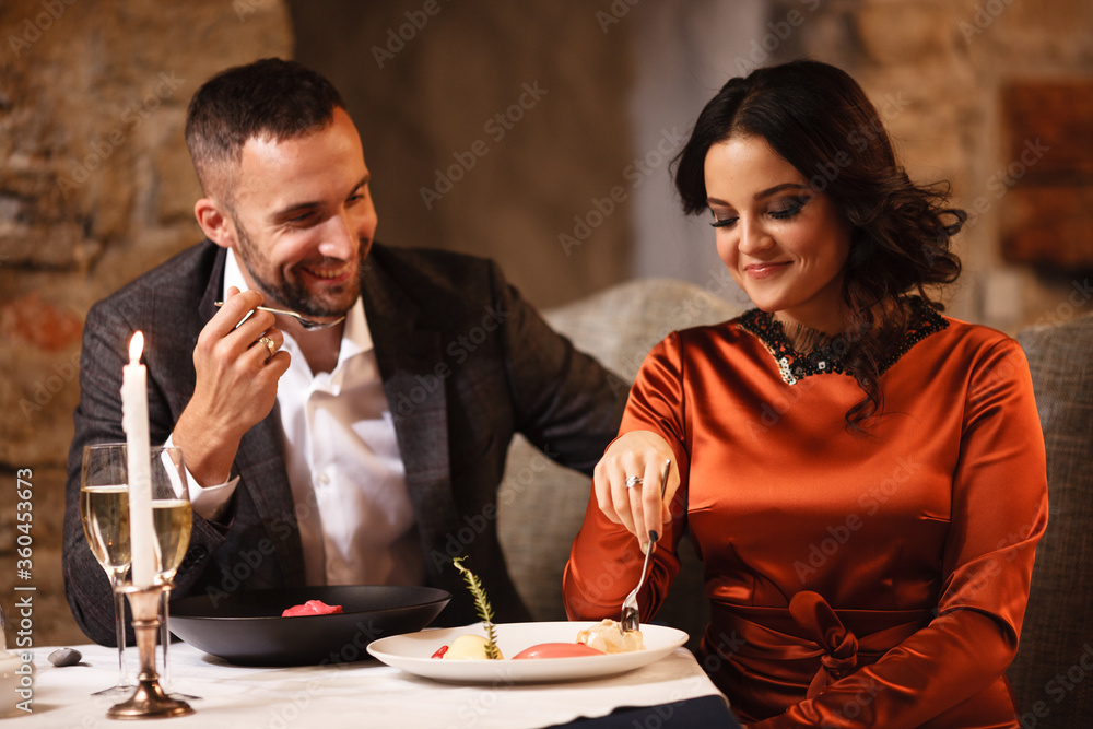 Romance and dating concept. Young couple man and woman celebrating and eating delicious dessert in restaurant. Two people male and female in elegant evening suit and dress on romantic dinner Romance and dating concept. Young couple man and woman celebrating and eating delicious dessert in restaurant. Two people male and female in elegant evening suit and dress on romantic dinner