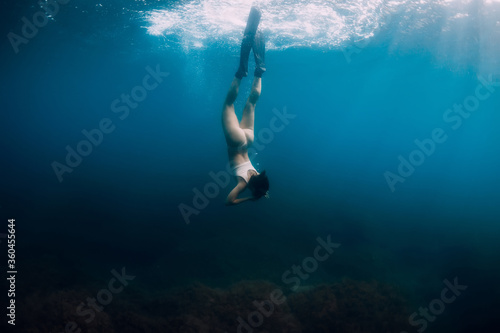 Woman free diver with fins dive to bottom underwater. Freediving in ocean