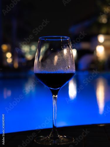 Sharp wine glass with the pool and blurred hotel lights background