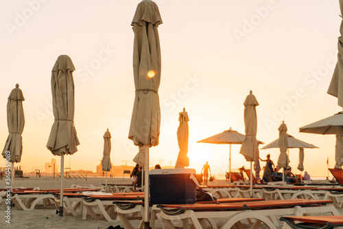 Bright hot summer beach sunset with umbrellas.