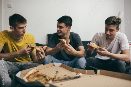 teenager boys eating pizza at home