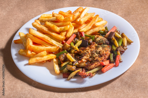 A nice plate of roasted chicken, seasoned with herbs, pepper, salt, oregano, and garlic. Also accompanied by vegetables fried on olive oil.
Accompanied by French fries on a white plate.