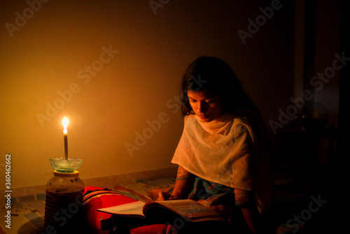 Fotografija A young girl studying at home with candlelight after electricity load shedding at Dhaka City, Bnagladesh