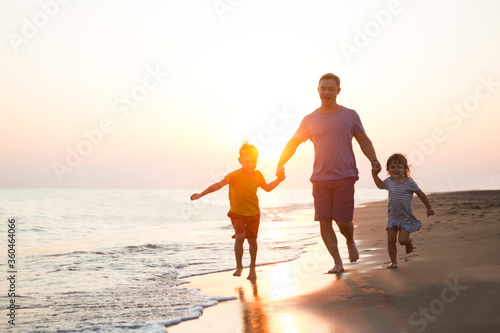 happy  family father and two children playing on the beach  run at the sunset time. 