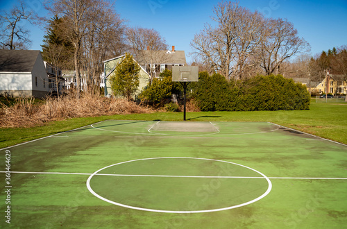 green recreational basketball court in a park with houses in background