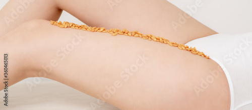 Wax beans or seed in row on legs of young woman lying on white background
