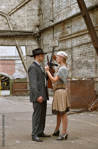 Two models get dressed up in 1930's style vintage clothing and act the part of the gangster duo Bonnie and Clyde. They are seen in the ruins of an old demolished factory.