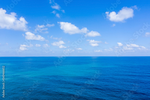 Aerial view of clear Ocean water with blue cloudy sky. 