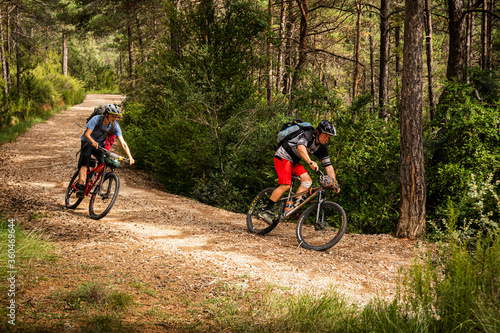 Two mountain bikers on a forest road in the low Pyrenees. Huesca, Spain.