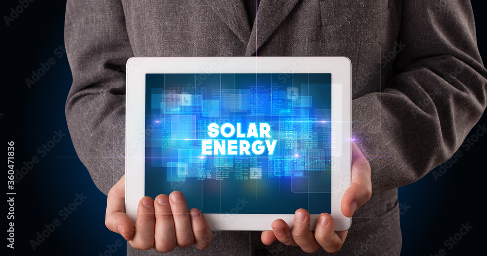 Young business person working on tablet and shows the inscription: SOLAR ENERGY Young business person working on tablet and shows the inscription: SOLAR ENERGY