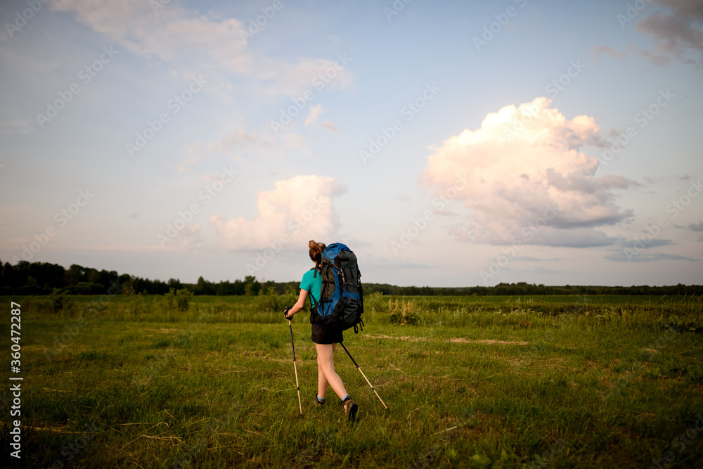 rear view of woman with sports outfit who walking along summer grassy field
