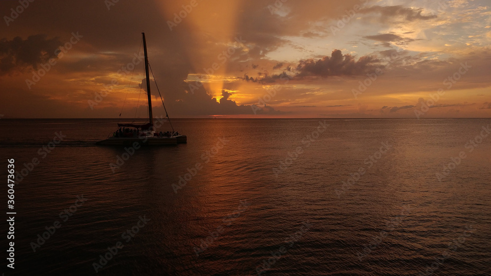 Fototapeta premium A calm sunset over the ocean in Jamaica with a boat