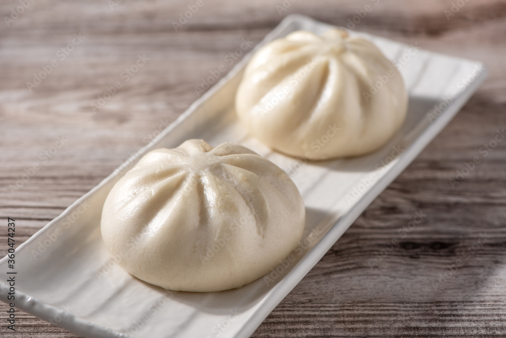 Delicious baozi, Chinese steamed meat bun is ready to eat on serving plate and steamer, close up, copy space product design concept. Delicious baozi, Chinese steamed meat bun is ready to eat on serving plate and steamer, close up, copy space product design concept.