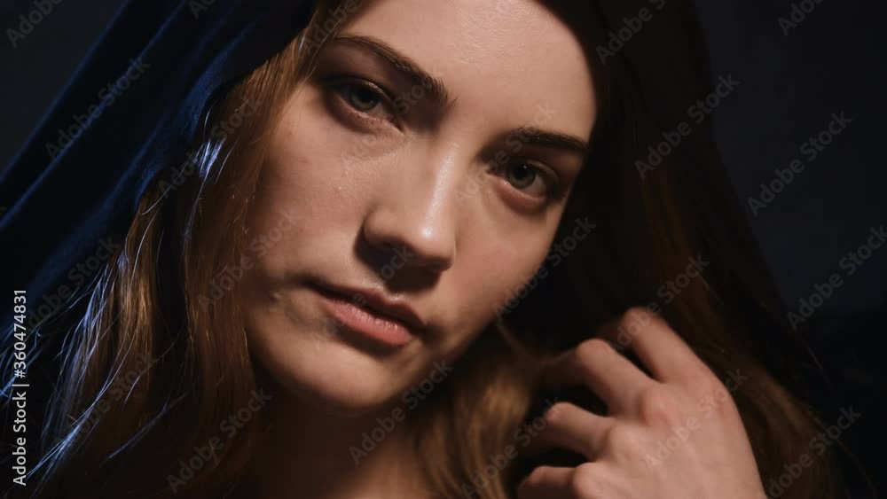 A large portrait of an attractive blonde girl in a hood flirts and flirts on camera seducing and conjuring. Low key holiday halloween and masquerade. Woman sedator A large portrait of an attractive blonde girl in a hood flirts and flirts on camera seducing and conjuring. Low key holiday halloween and masquerade. Woman sedator