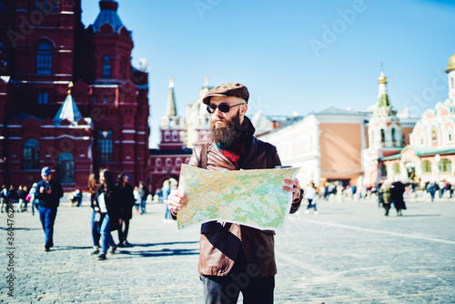 Photography Trendy male tourist holding map and searching location while resting on Moscow r