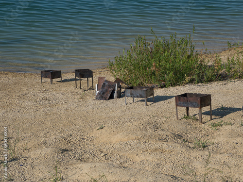 Iron barbecue. Left garbage on the shore of the lake. Human pollution of nature