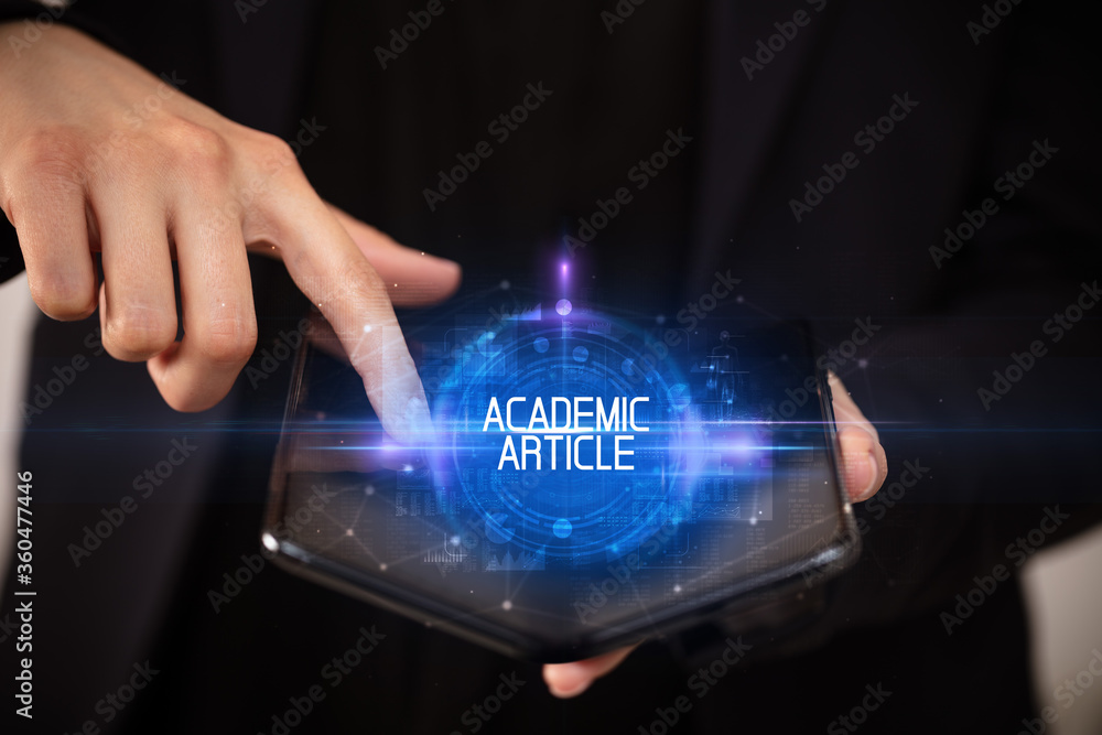 Naklejka premium Young man holding a foldable smartphone with ACADEMIC ARTICLE inscription, educational concept