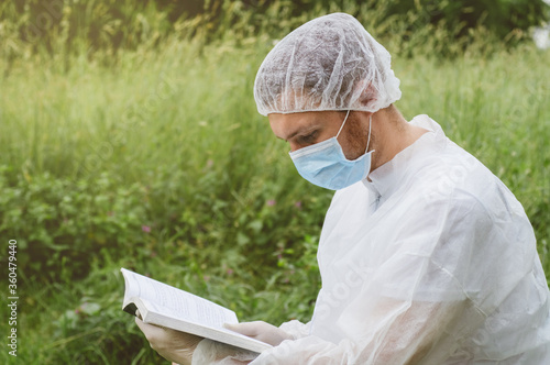 Man reading a book in protective clothes. Covid-19 photo