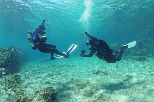 Diving instructor and student in underwater exercise. Instructor teaches student to dive. Underwater scuba diving education and training.