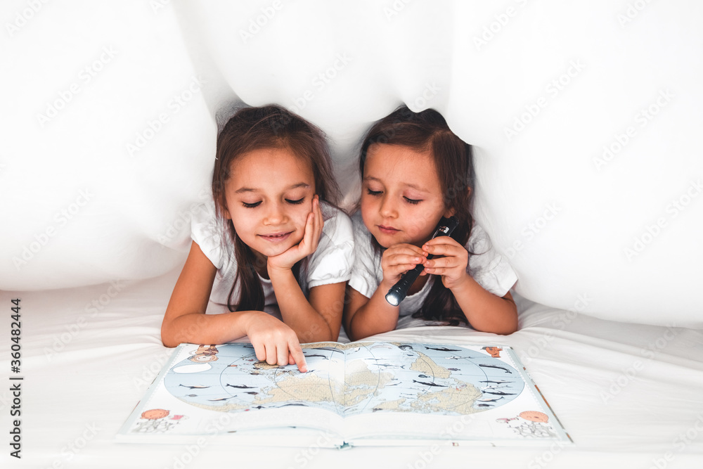 two girls reading under blanket two girls reading under blanket