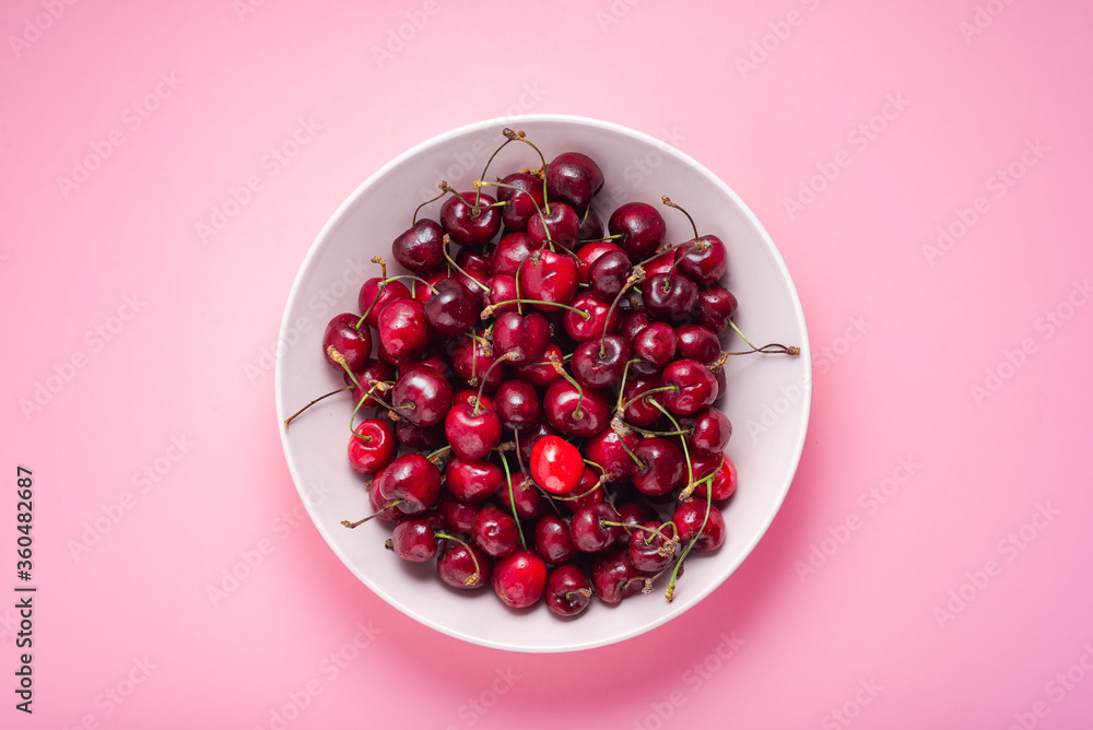 Fresh cherries in a bowl on a pink background, top view Fresh cherries in a bowl on a pink background, top view