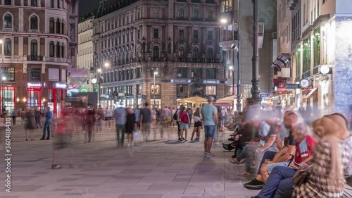 People walking in the Old city center of Vienna in Stephansplatz night timelapse. Shops and restaurants around, crowded place photo