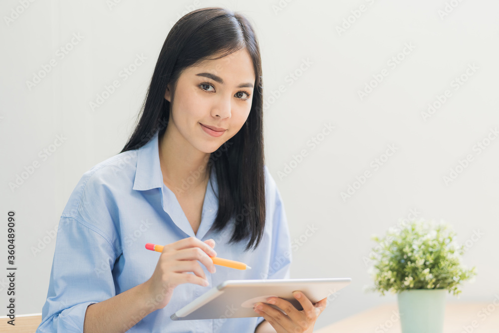 Beautiful asian women conferencing work from home with tablet taking on headphones in the morning. Smiling charming happy young female stay at home. Beautiful asian women conferencing work from home with tablet taking on headphones in the morning. Smiling charming happy young female stay at home.