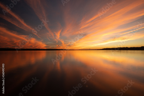 Colorful Golden and Orange Sunset Sky Over River With Reflections in the Calm Water