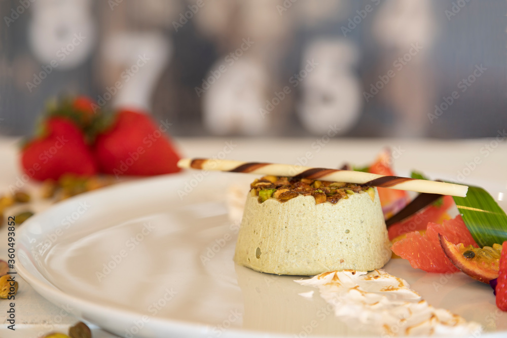Delicious dessert with pistachio and fresh fruit on a white plate Delicious dessert with pistachio and fresh fruit on a white plate
