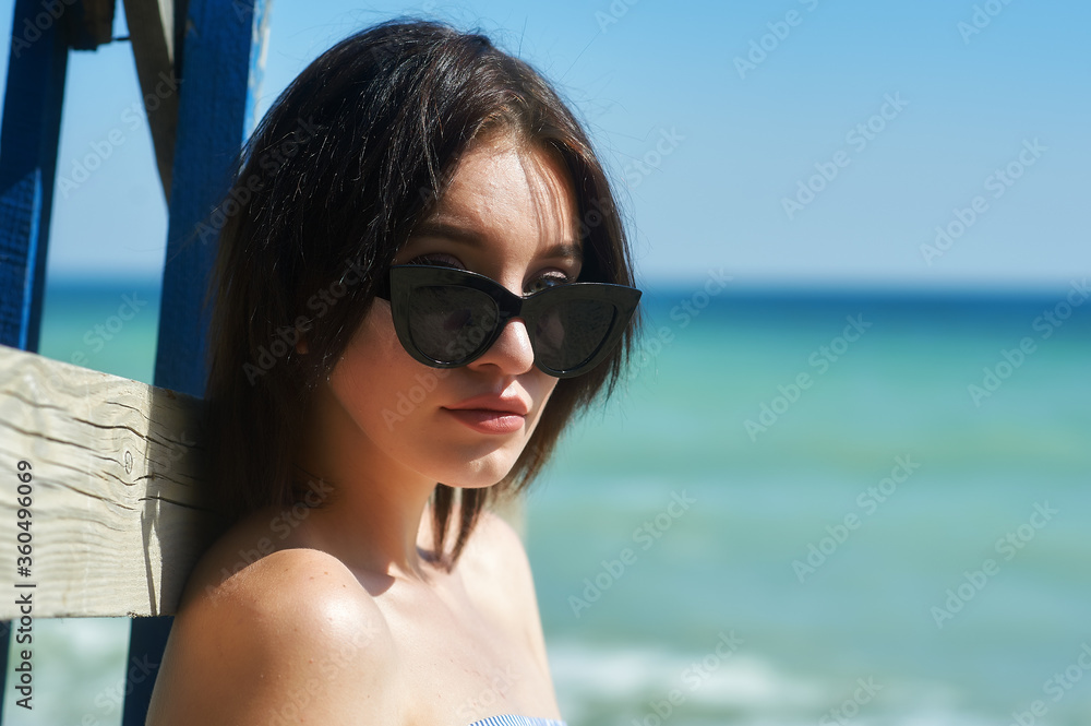 Portrait of a young beautiful girl in sunglasses on the sea coast Portrait of a young beautiful girl in sunglasses on the sea coast