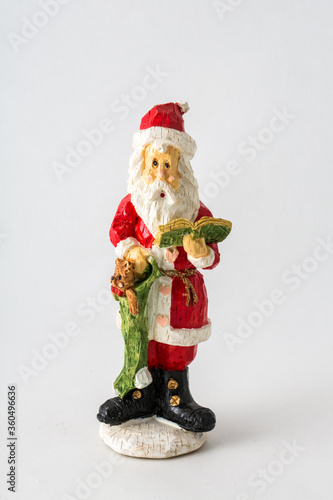 a styalized hand carved Santa Claus figurine, reading a book, on an isolated white background. photo