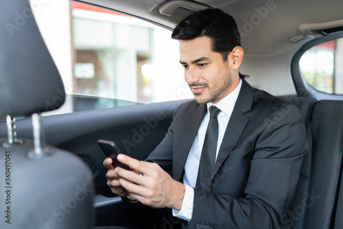 Young Businessman Using Smartphone In Taxi